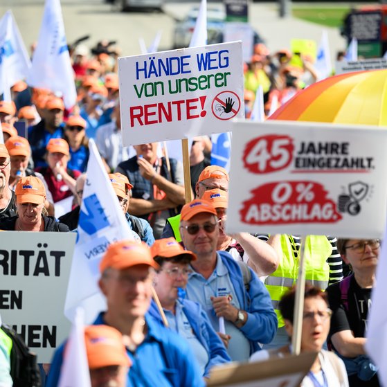 Demonstrationszug des VdK Bayern mit Menschen in orangen Mützen, die Schilder mit Forderungen gegen Sozialabbau und für Rentenrechte halten
